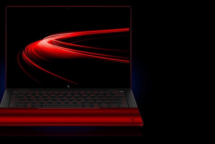 A sleek red laptop with a minimalist design, displaying vibrant red light trails on its screen, set against a dark background.