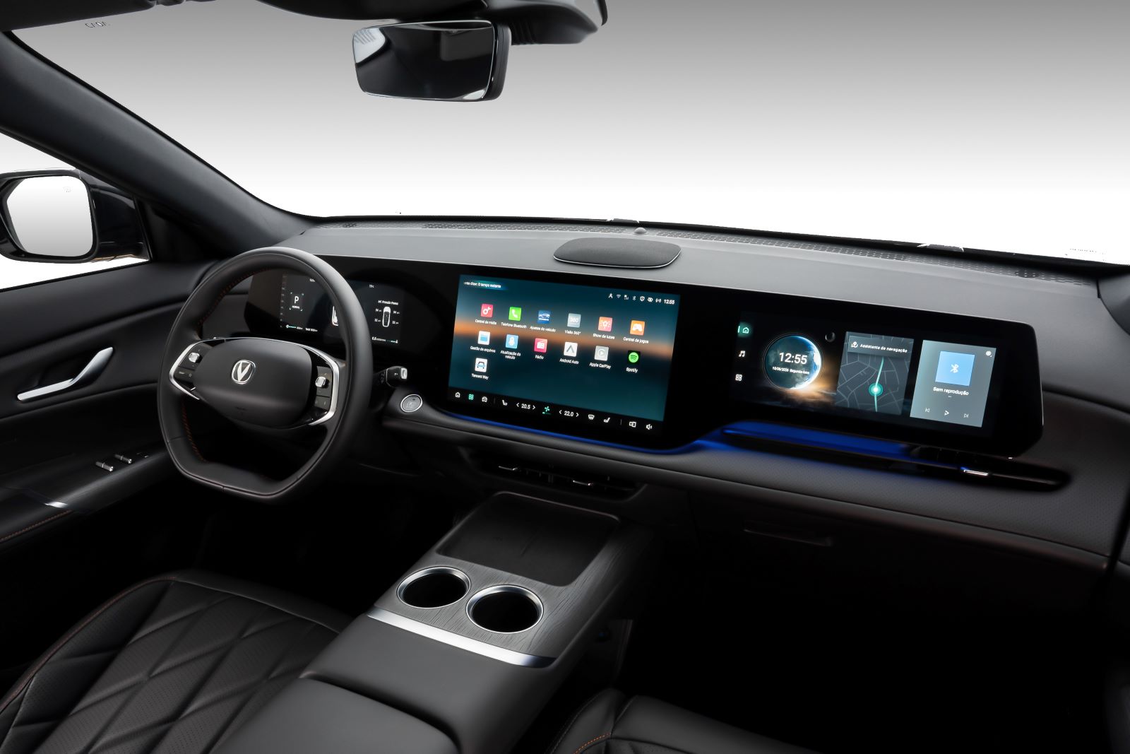 Interior de um carro moderno, mostrando o volante, painel digital e tela central com aplicativos diversos.