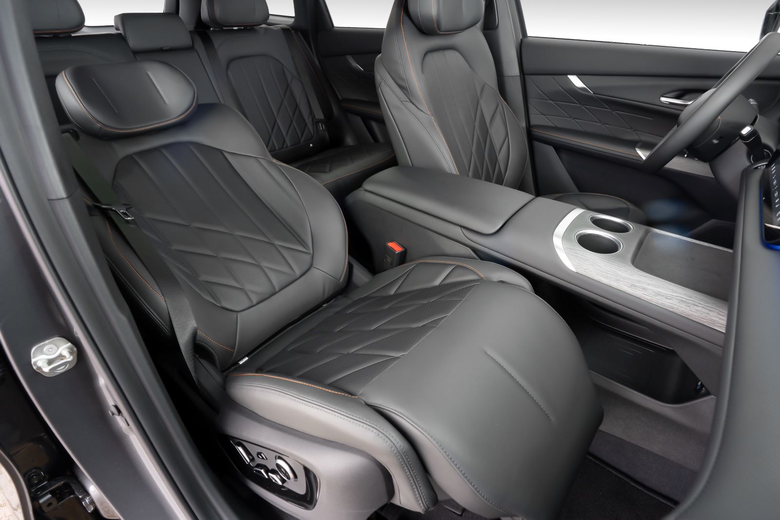Interior de carro com assentos em couro preto, detalhados em costura em tom de laranja, incluindo um console central com porta-copos.