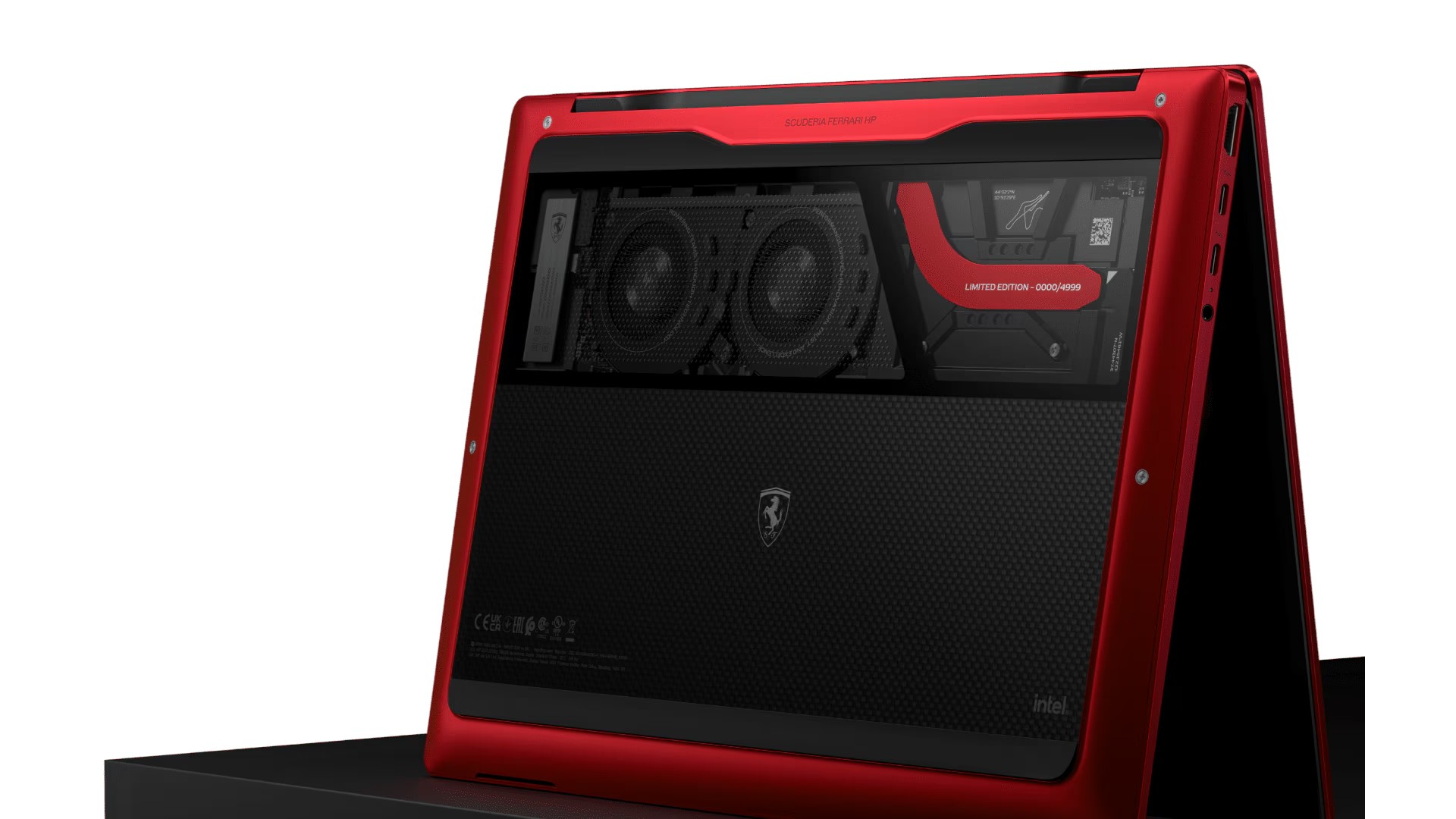 Close-up of a limited edition red laptop featuring a sleek design and Ferrari logo, showcasing dual cooling fans and a carbon fiber texture on the back.