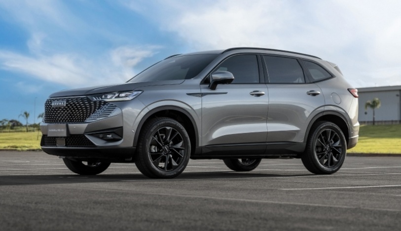 A silver SUV parked on a paved surface with a grassy area and blue sky in the background.