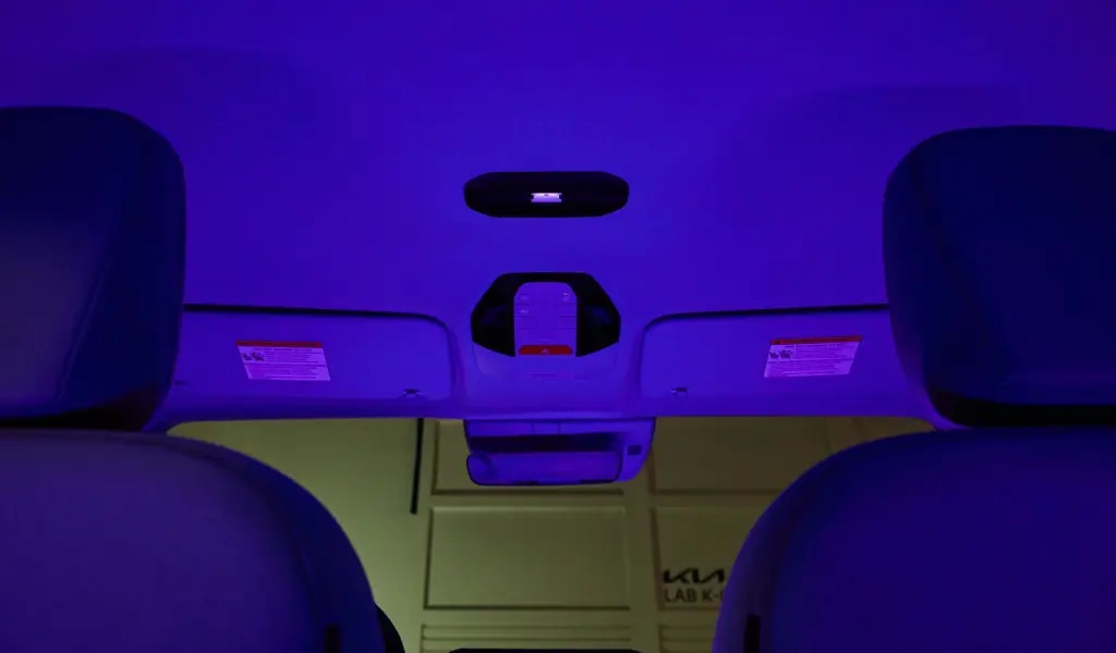 Interior view of a car roof with purple ambient lighting and overhead controls visible.