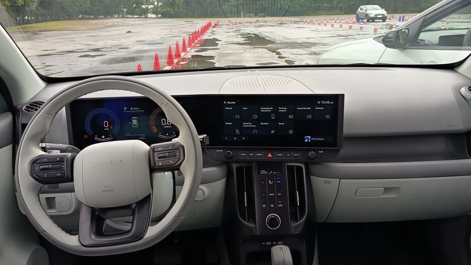 Interior de um carro moderno com volante, painel digital e tela central.
