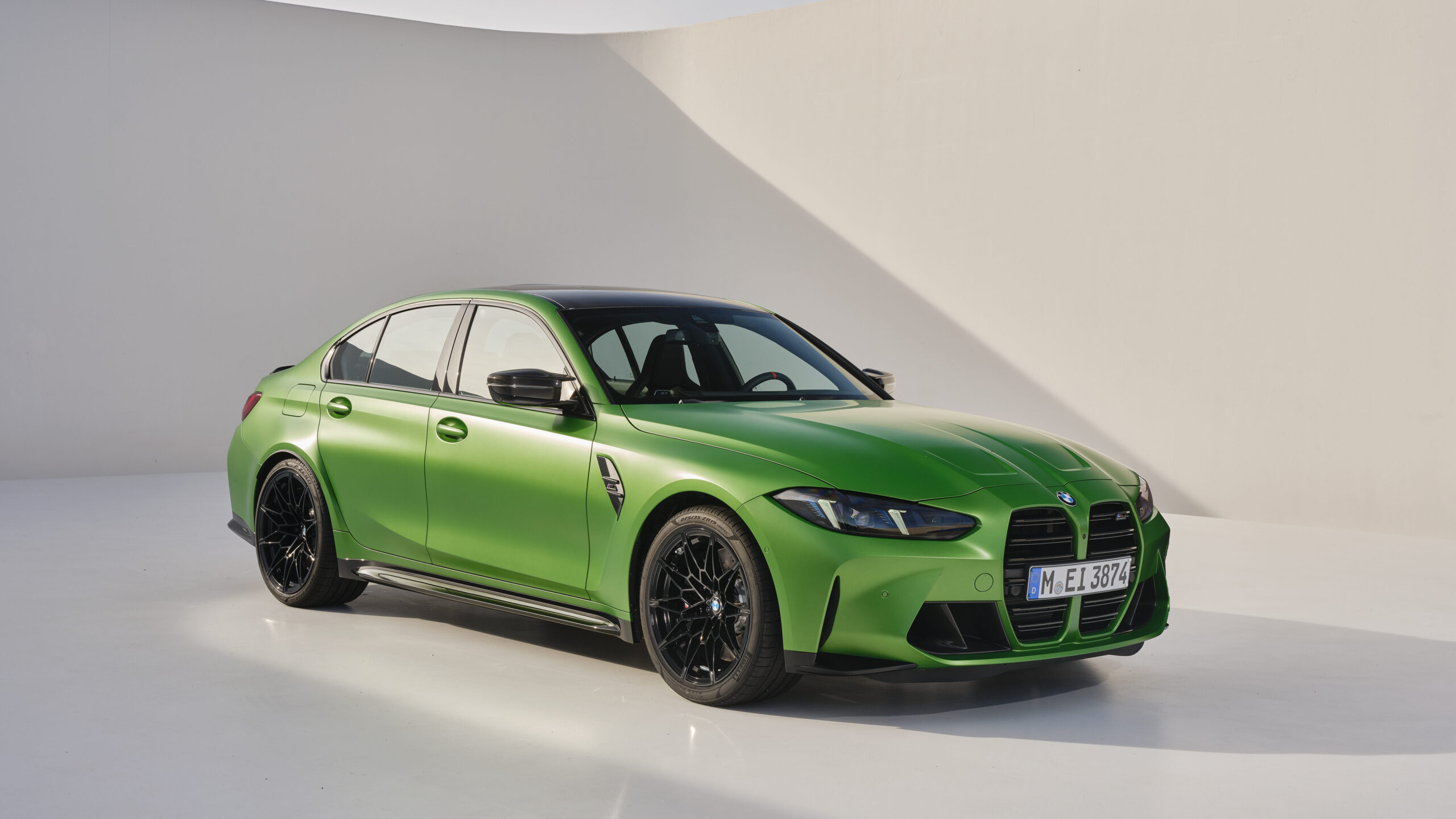 A vibrant green sports sedan with a black roof and sleek design, featuring bold front grilles and black alloy wheels, set against a minimalist white backdrop.