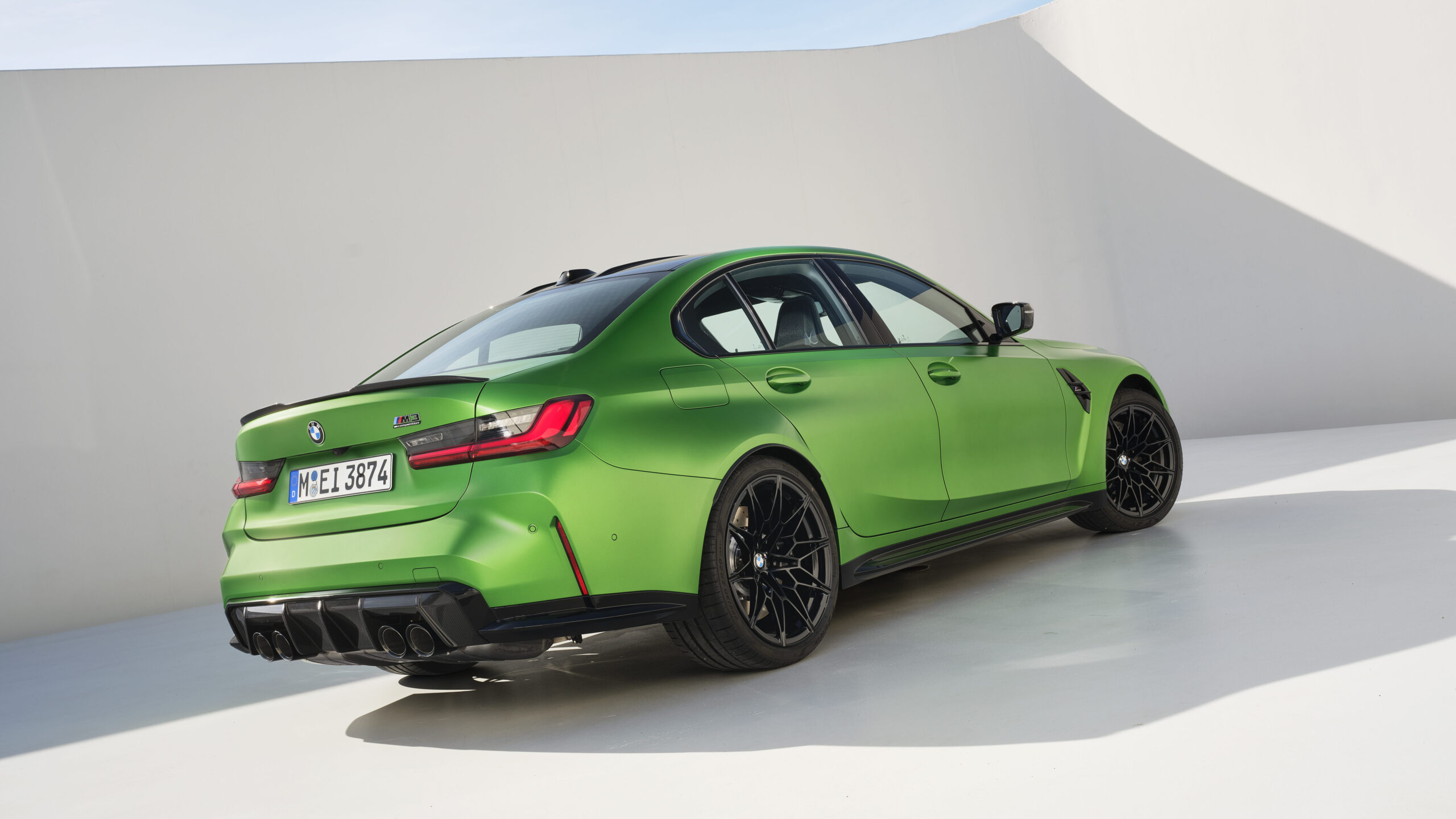 A green BMW M3 sports car displayed at an angle, showcasing its sleek design and rear features with a minimalist white background.