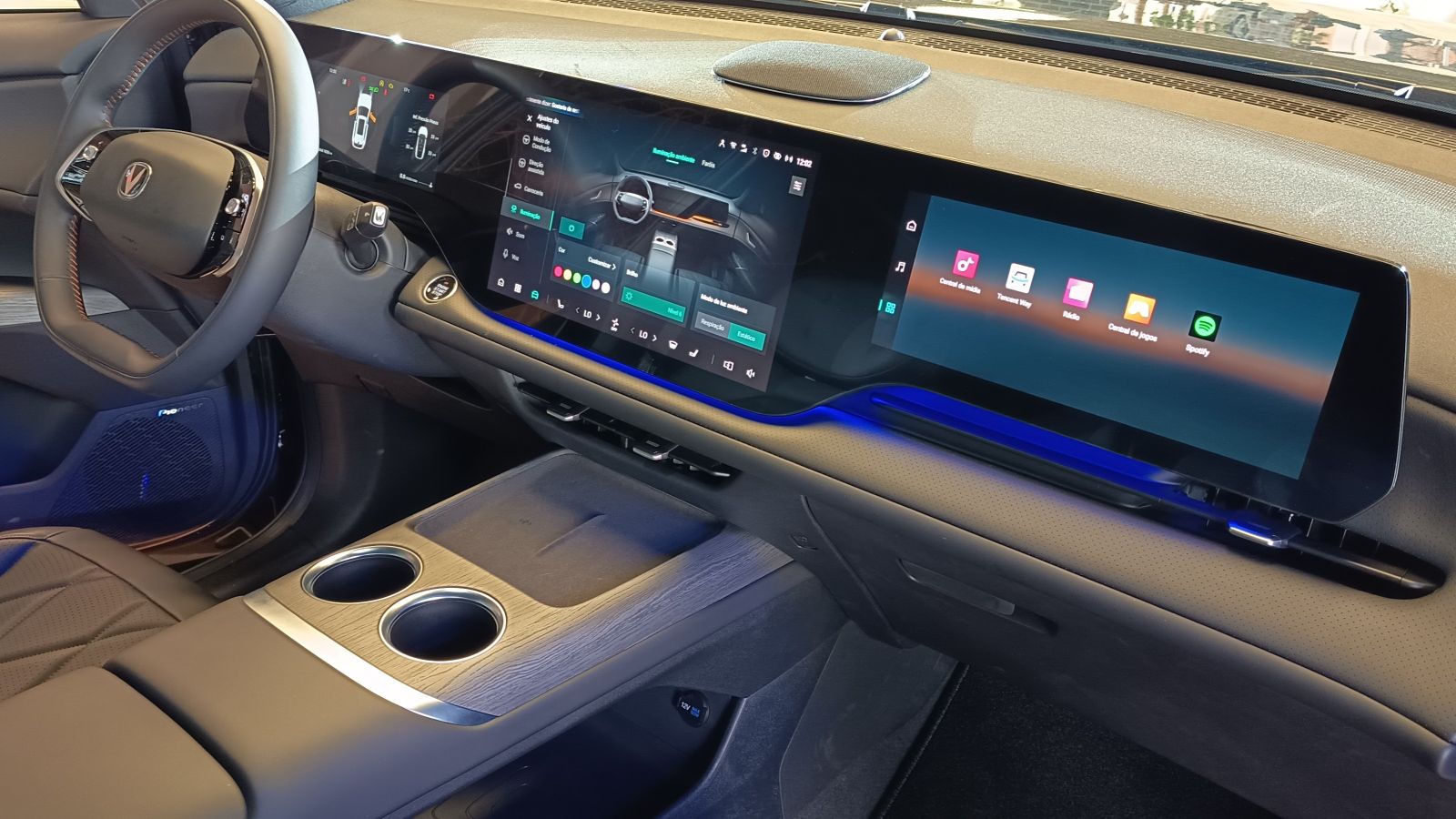 Interior moderno de carro com painel digital, volante e console central com dois porta-copos.