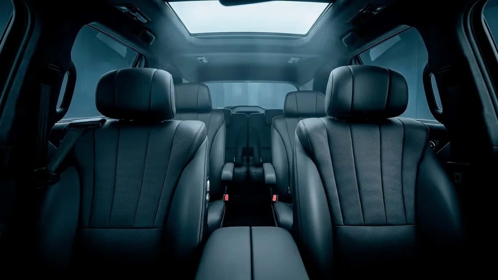 Interior view of a car showcasing black leather seats and a sunroof, with a dark and moody ambiance.