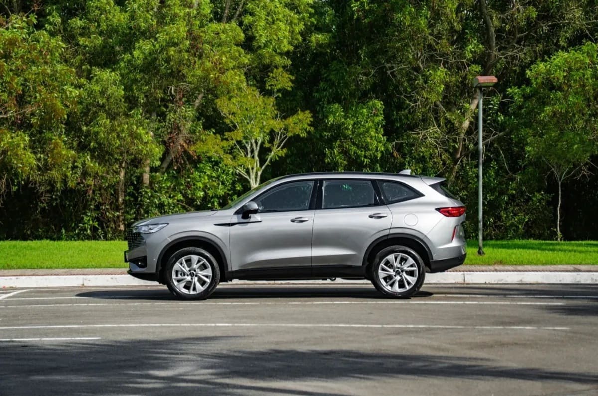 A silver SUV parked on the side of a road, surrounded by lush green trees and grass.