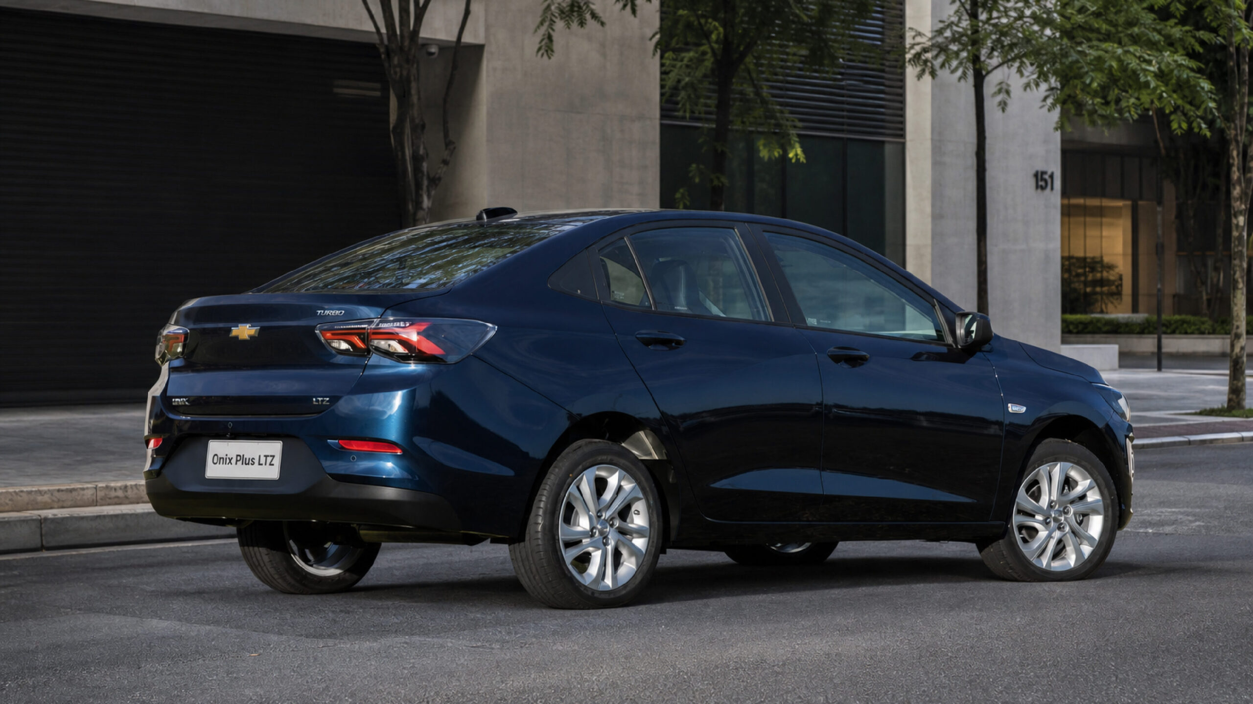 A blue Chevrolet Onix Plus LTZ parked on a city street, showcasing its sleek design and modern features.