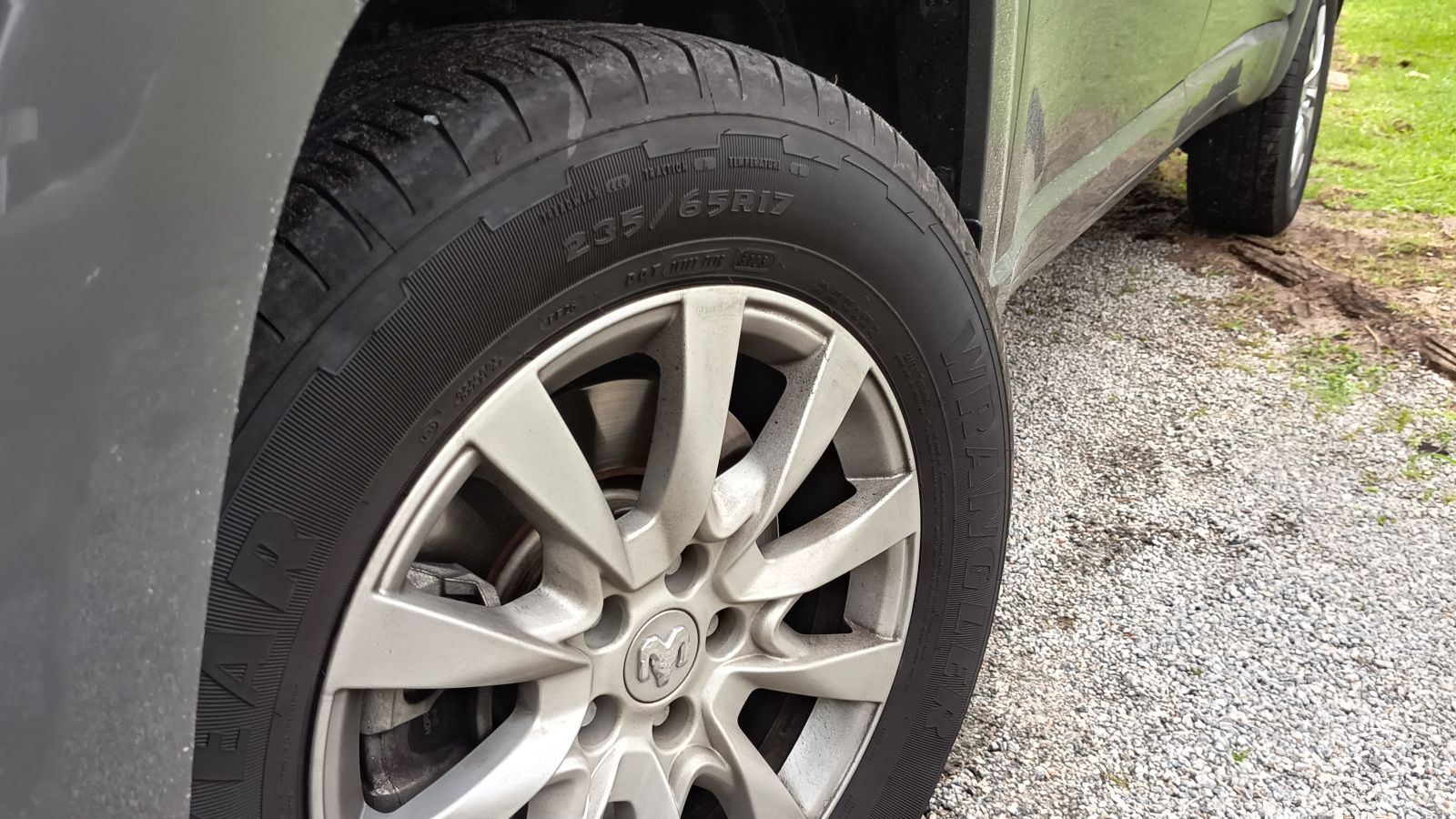 Imagem de um pneu de carro próximo a uma roda, mostrando detalhes do aro e da banda de rodagem.