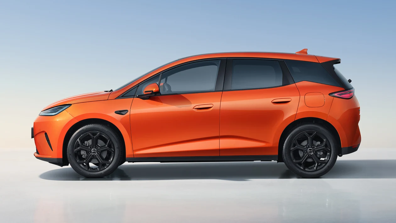 Carro elétrico laranja visto de perfil, com detalhes em preto, em fundo neutro.