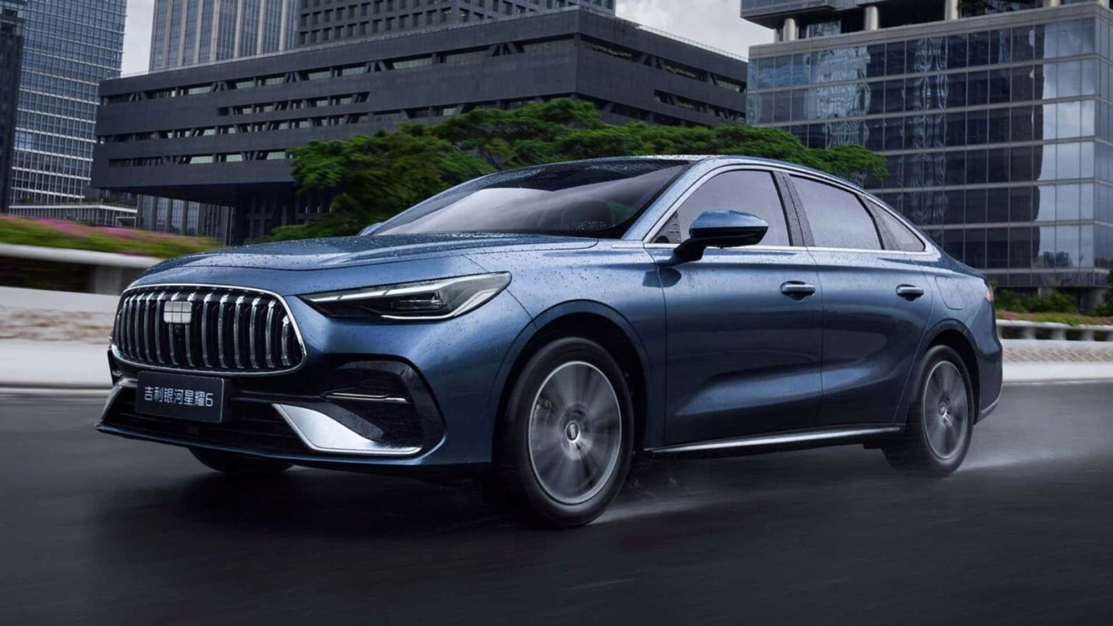 Um carro azul moderno em movimento em uma estrada urbana, com prédios e vegetação ao fundo.