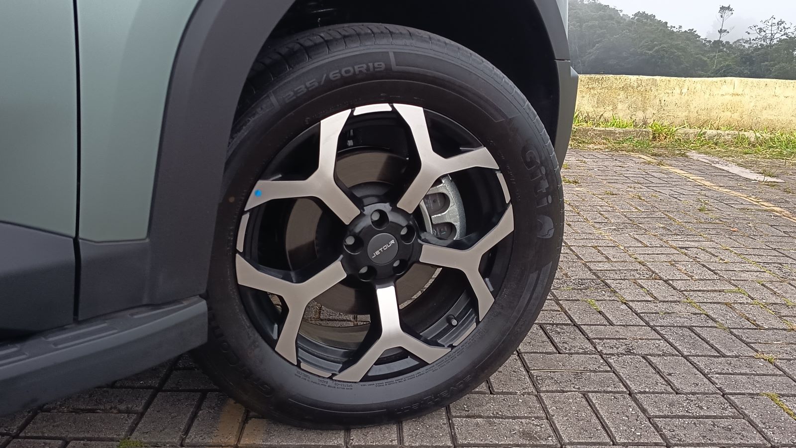 Roda de carro moderna com aro prateado e preto, exibindo pneu de perfil 235/60R19.