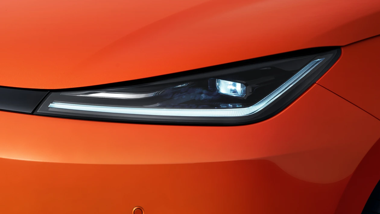 Detalhe do farol de um carro laranja com um design moderno e elegante.